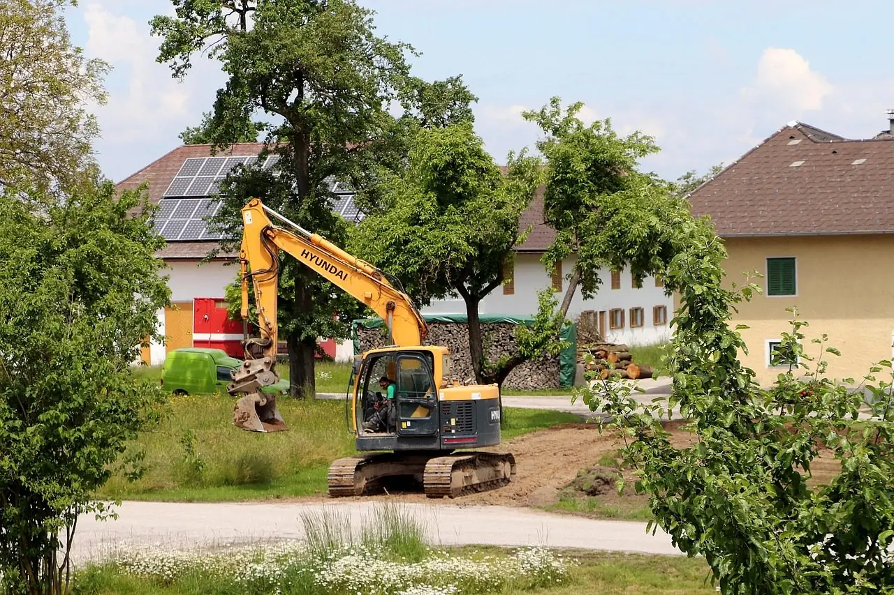 Excavator working in a backyard next to houses and trees